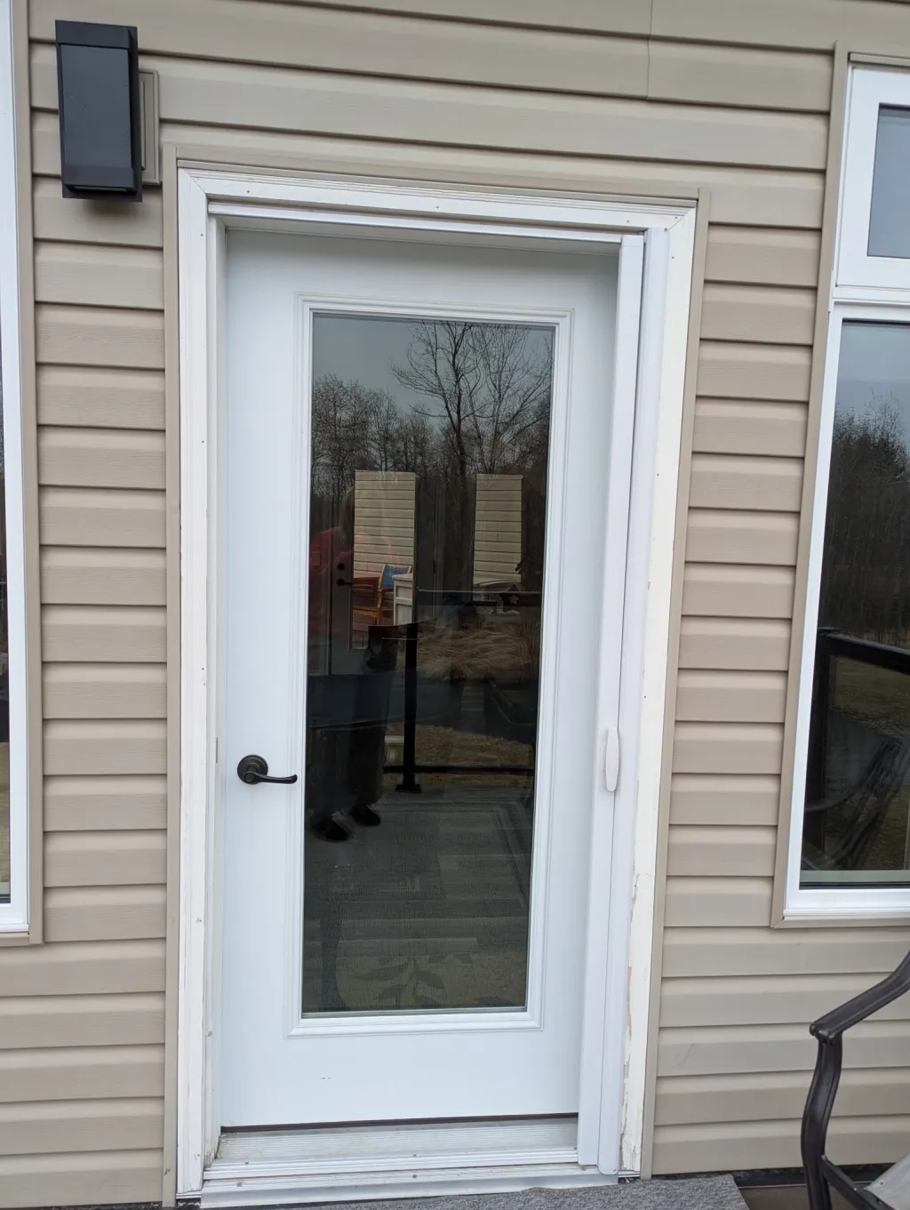 Single entry door before retractable screen installation — white frame on beige siding