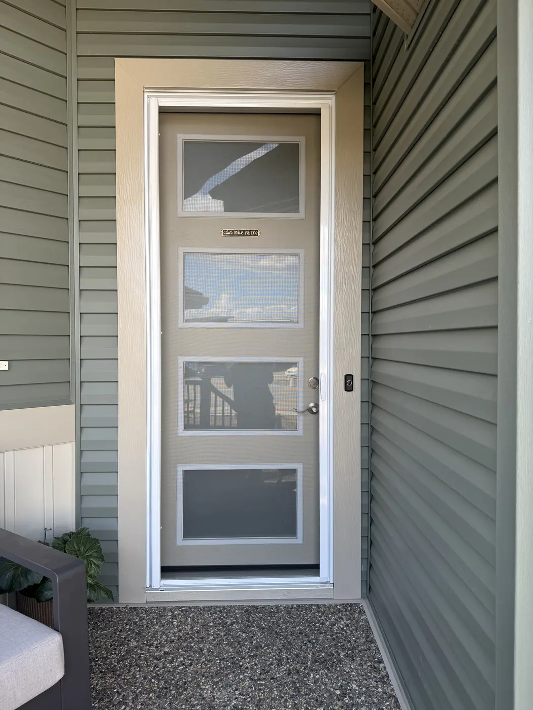 Four-panel modern entry door with Mirage retractable screen retracted into its side cassette — sage-green sided home