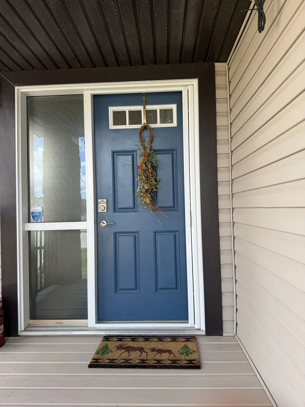 Navy blue front entry door with autumn wreath and sidelight — Mirage retractable screen on an Edmonton home