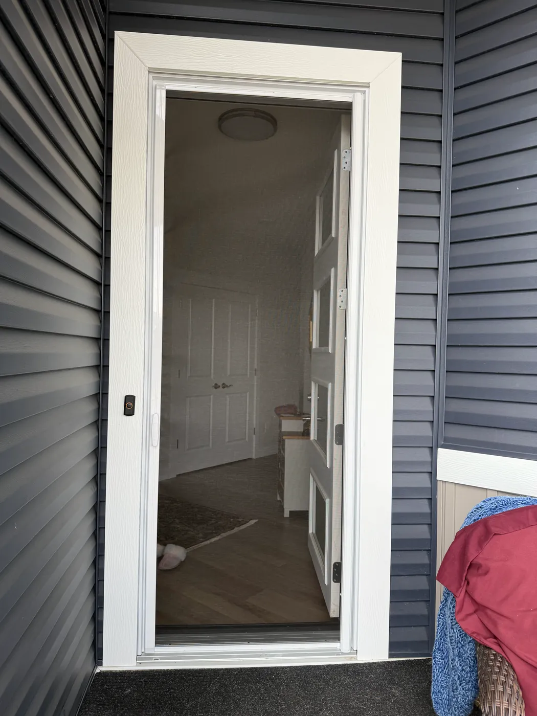 Mirage retractable screen extended across a single entry door on a modern charcoal-sided home