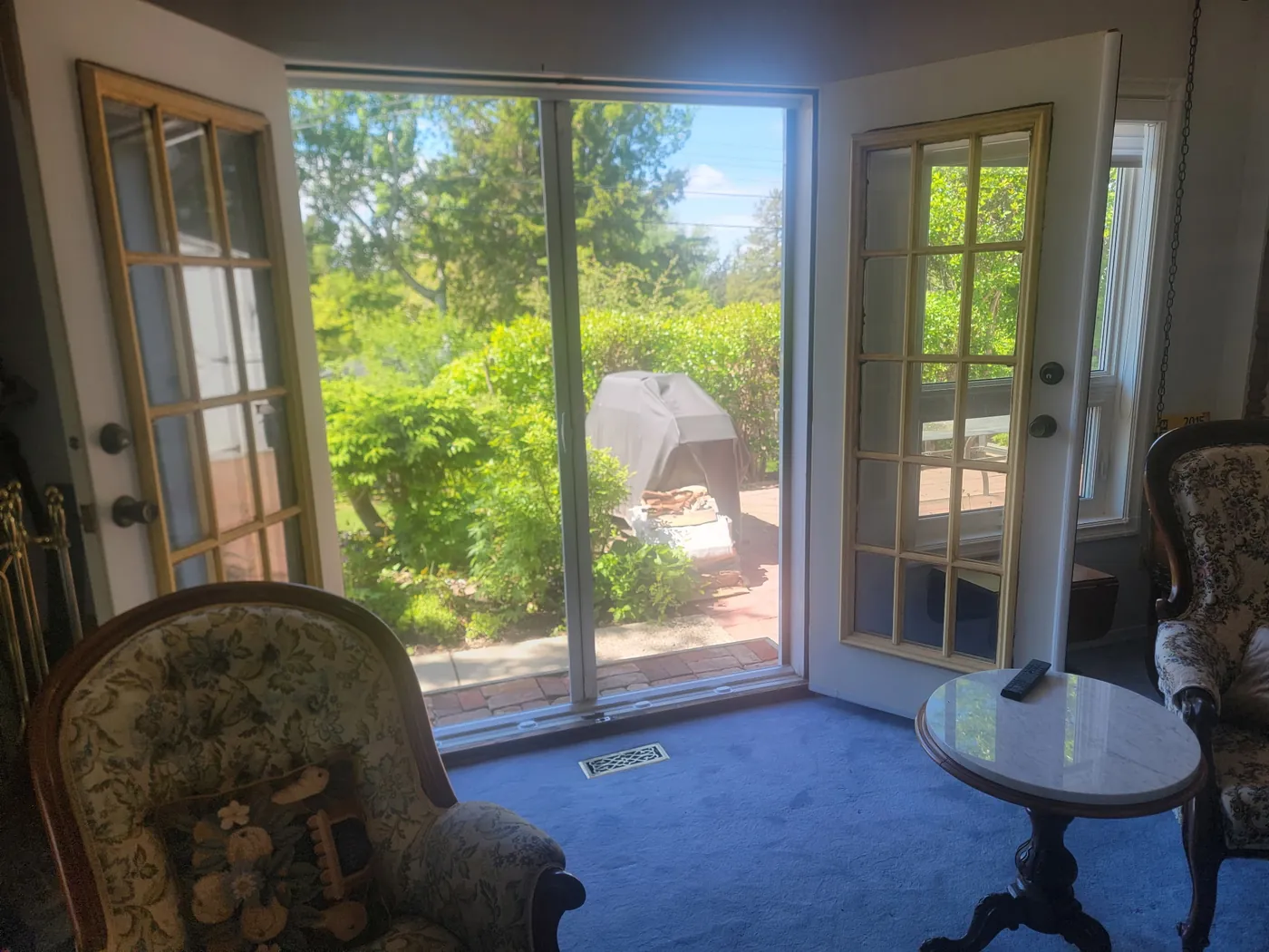 Living room looking out through French garden doors fitted with a Mirage retractable screen to a sunlit backyard