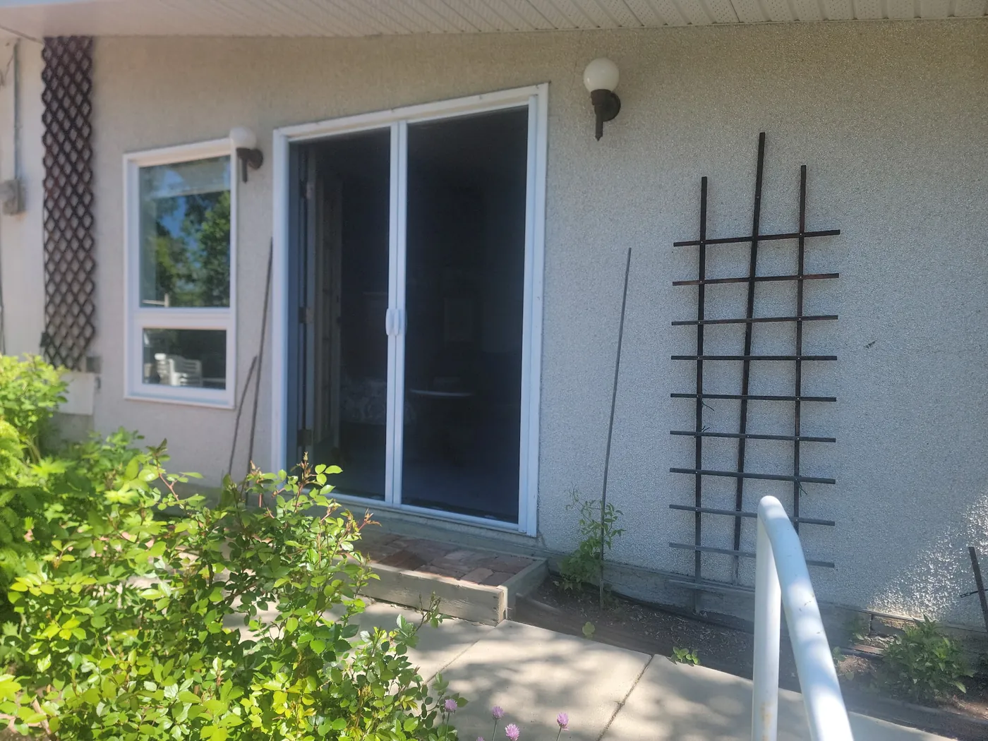 Mirage retractable screen on a garden patio door framed by lush greenery and a decorative wall trellis